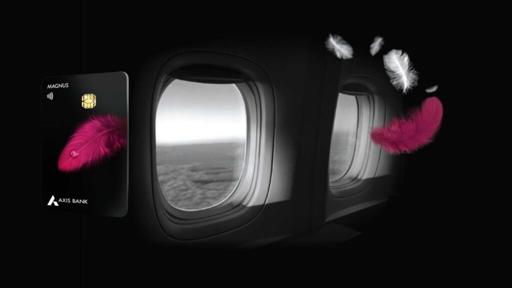 A black Axis Bank Magnus Credit Card with a pink feather design floating next to two dark airplane windows, suggesting high-end air travel.