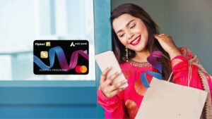 Smiling Indian woman holding a smartphone and shopping bags, with a graphic of the Flipkart Axis Bank Credit Card overlaid.