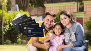 Happy NRI family (father, mother, and daughter) smiling outdoors, with a fan of premium Indian credit cards overlaid, including cards from HDFC, Axis, RBL, and Kotak.