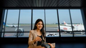 Indian woman swiping a credit card at an airport lounge counter with aircraft visible in the background, representing the best airline credit card in India for frequent international travelers.