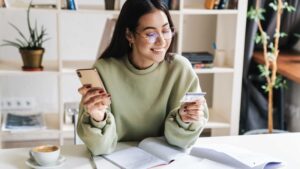 Young woman learning about the best first credit card India while managing finances on her phone and holding a credit card.