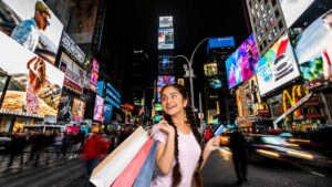 Indian woman shopping overseas with a credit card in a busy city market at night, illustrating how credit card forex markup in India affects international spending.