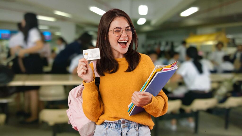 Young woman holding a credit card on a college campus, symbolizing how to apply for credit card in India.