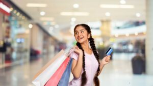 Woman shopping happily in a mall holding bags and a credit card — representing financial freedom and smart spending with general credit cards India.