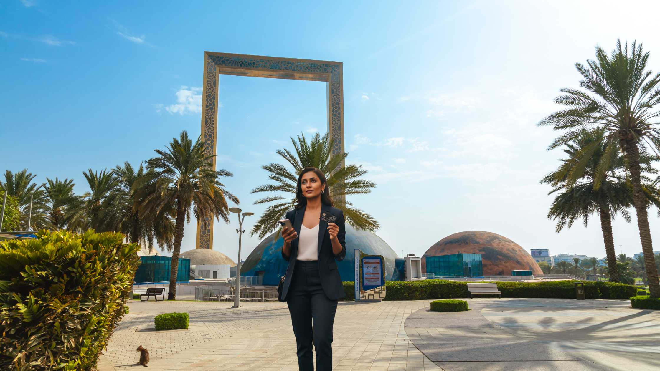 Modern Indian woman holding a credit card and smartphone in an outdoor urban setting, symbolizing confidence and financial awareness related to improving credit score for credit card in India.